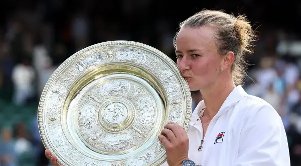 Tenisistka całuje puchar Wimbledonu.